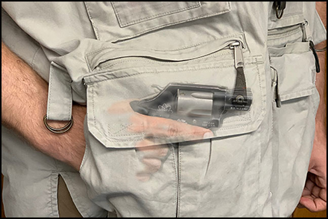 A mang holding a revolver in the pocket of his vest